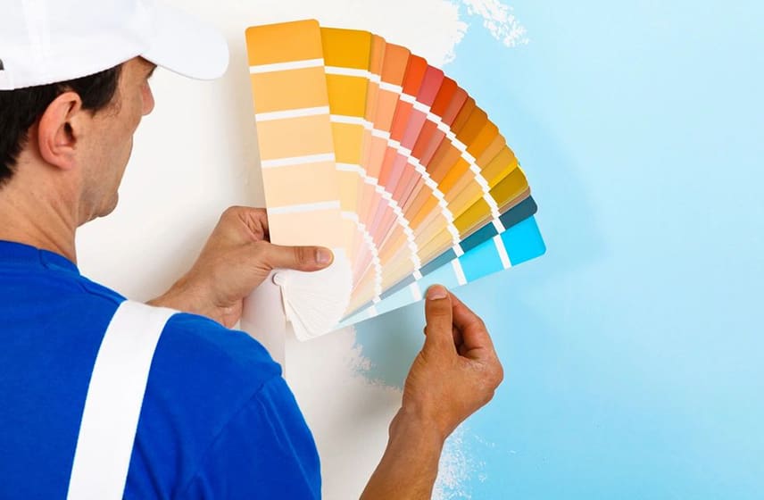 A man holding up a fan of paint.