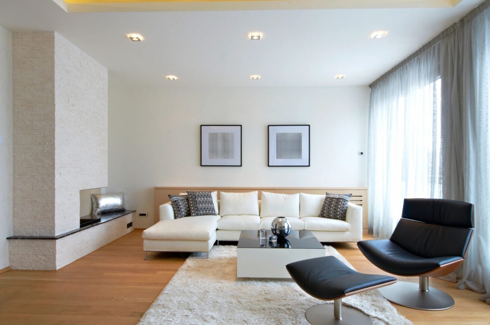 A living room with white furniture and a rug.